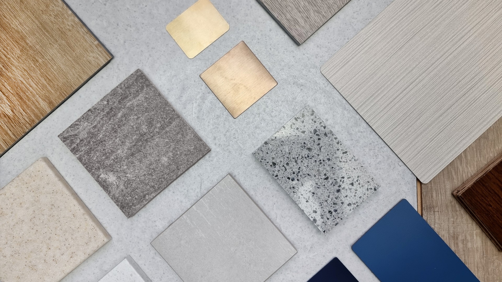 creative composition of interior material samples contains panels and tiles. stylish interior moodboard including terrazzo, quartz, stone tiles, blue laminated, wooden flooring tiles, gold stainless.